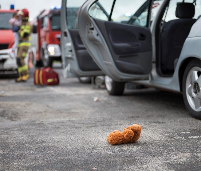 Car accident - teddy bear lying on the road and baby in lifeguard hands