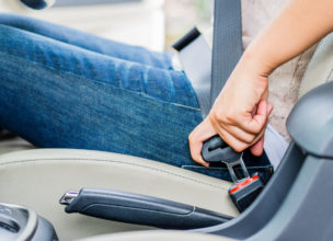 Closeup woman hand sitting inside car fastening seat belt. Safety belt safety first.